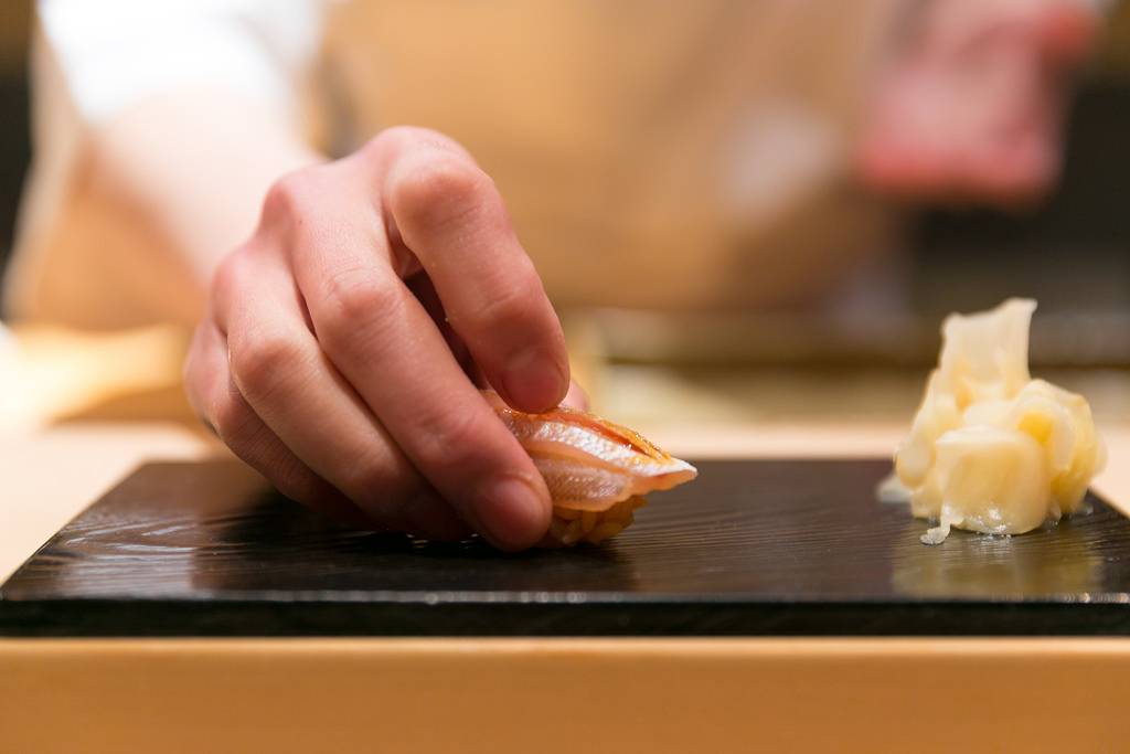 Sushi chef placing sushi on board