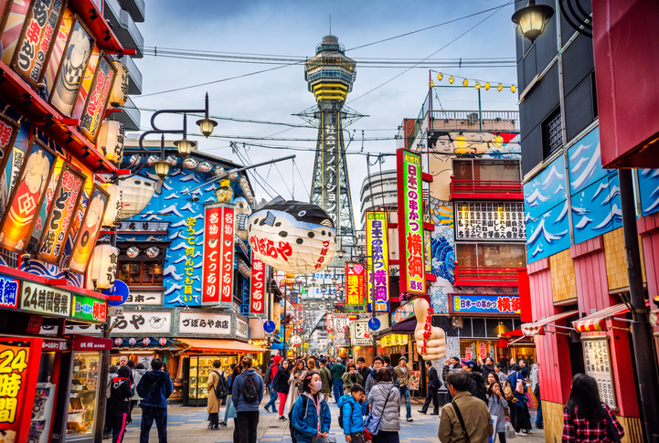 Osaka Tower and view of the neon advertisements in Shinsekai district at dusk, Osaka, Japan