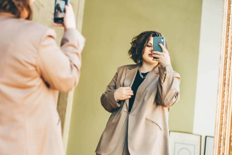 Plus size woman in business clothes making selfie.