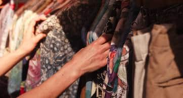 A young woman is browsing a rail of clothes at a street market