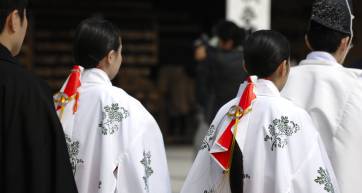 Two shrine maidens seen from behind, with long hair and white robes