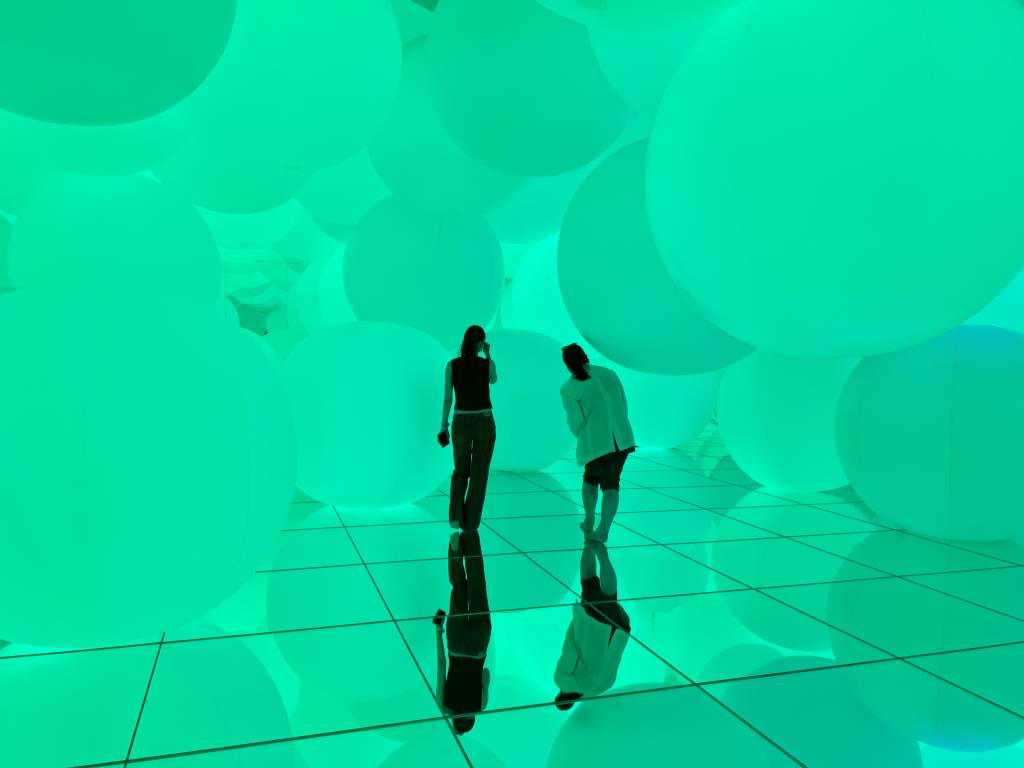 two people walk around teamLab Planets, the spheres room.