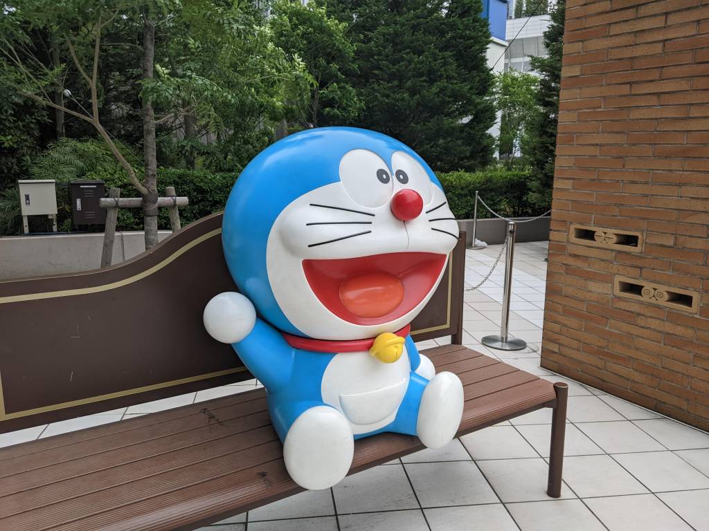 A Doraemon statue sitting on a bench