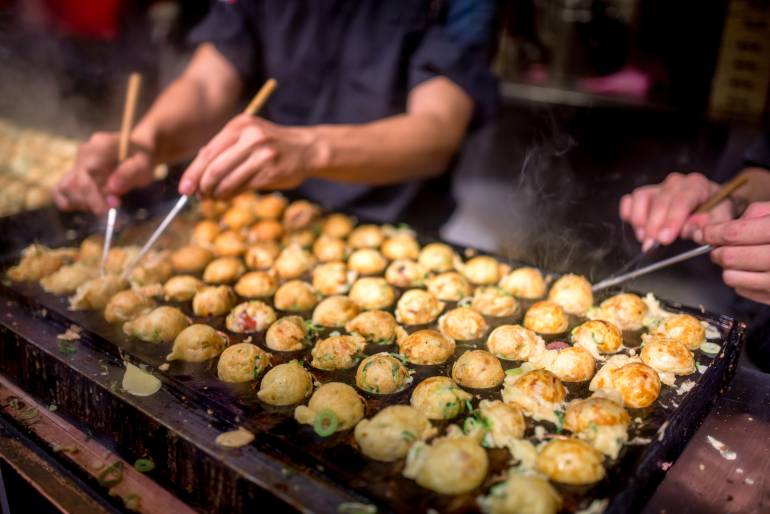 Chef turning takoyaki on a grill